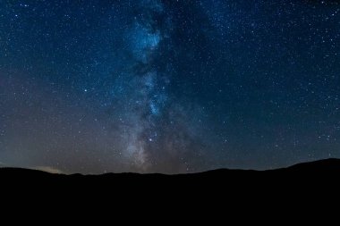 Samanyolu 'nun altındaki dağ silueti ve sihirli yıldızlı gökyüzü. Evrenin sonsuzluğunu ve geceleri yıldızları düşünüyorum..
