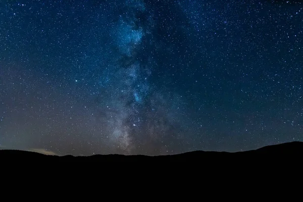 Samanyolu 'nun altındaki dağ silueti ve sihirli yıldızlı gökyüzü. Evrenin sonsuzluğunu ve geceleri yıldızları düşünüyorum..