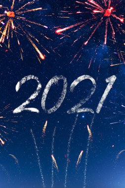 2021 havai fişekler arka planda güzel, yıldızlı, mavi bir gökyüzünde. Parlak ve güzel havai fişekler ve roketler 2021 yılını karşılamak ve başlatmak için. Mutlu yıllar 2021, Noel kutlaması.