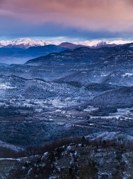 Snowy winter mountainous landscape on a cold sunrise. Icy landscape with hoarfrost. Mountain range of Bellmunt, Osona, Catalonia, Spain with Pyrenees at background, vertical.