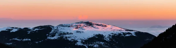 日の出や日没の雪の山のピークのパノラマビュー 静かでリラックスした自然山の自然景観 夕暮れ時に山の中でオレンジと暖かい色の自然背景風景 — ストック写真