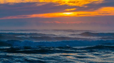 Gün batımında deniz manzarası ya da gün doğumunda okyanus dalgaları ve gökyüzünde turuncu renkli bulutlar. Plajda tatil kavramı, boş zaman, seyahat, yaz, rutinden uzaklaşma ve rahatlama..