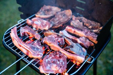 Grilled lamb chops. Meat cooking on the barbecue with burning embers. Preparing grilled meat on the garden barbecue.