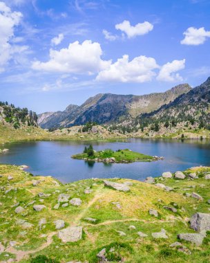 Güneşli bir yaz gününde yeşil çimlerle çevrili dağlarla çevrili güzel dağ gölü. Dağ gezisi ve yaz tatili kavramı. Circo Saboredo, Aran Vadisi Pireneleri, Katalonya, İspanya.