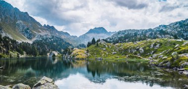 Dağ gölünün manzarası suya yansıyan dağlarla çevrili. Dağ gezisi, yaz tatili ve doğa kavramı. Circo Saboredo, Aran Vadisi Pireneleri, Katalonya, İspanya.