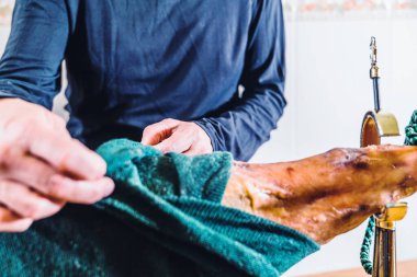 Anonim bir adam evdeki mutfakta jambon budu hazırlıyor. Jambonu jambon tutacağına koyuyorum. Jambonlu omuz hediyesi. İberya jambonu. Tipik İspanyol yemeği ve aperatifi..