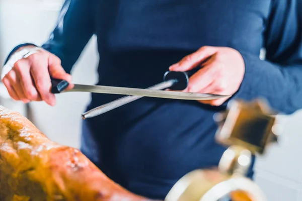 Anonymous person sharpening ham knife before cutting ham. Very well sharpened quality knife.