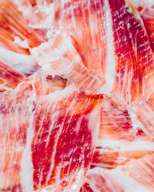 İberya jambonu ön planda iştah açıcı. İberya jambonu, Meşe palamudu ile beslenmiş Iberico jambonu. Pata negra, dilimlenmiş jambonun muhteşem görüntüsü. Tipik İspanyol yemeği ya da katalan yemeği. Dikey duvar kağıdı.