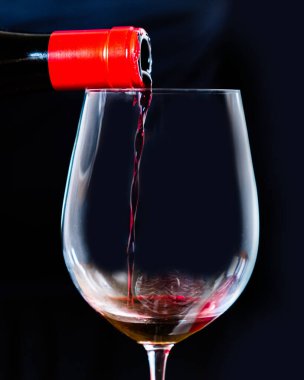 Sommelier siyah arka planı olan zarif bir kristal kadehte İspanyol siyah şarabı servis ediyor. Kırmızı şarabı şişeden siyaha dök..