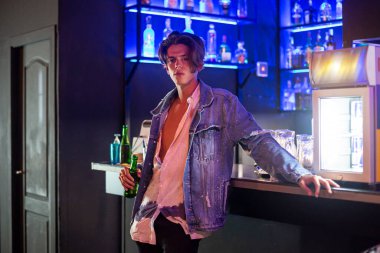 Bira ve bar geçmişi olan kot ceketli genç bir adamın yakın plan portresi..