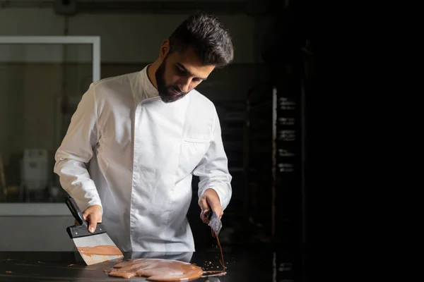 Pasta şefi mermer masada çikolatayı sertleştirmeye çalışıyor.
