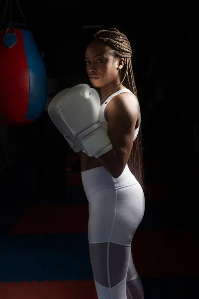 Portrait of Young afro american woman training boxing in gym with boxing gloves and white clothes.