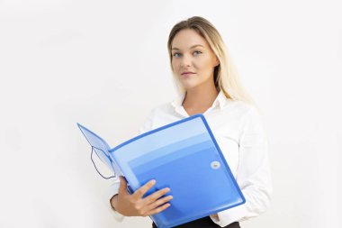 Güzel genç iş kadını elinde mavi klasörle kameraya bakıyor..