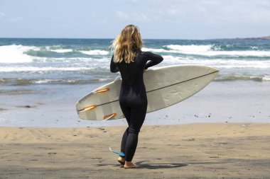 Sırtında sörf tahtası, arkasında deniz olan yaz sörfçüsü kız..