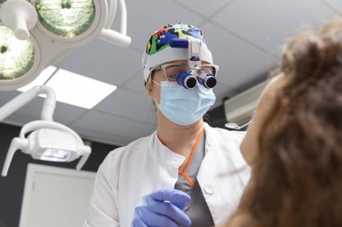 Diş hekiminde bir hasta üzerinde çalışan bir dişçi.