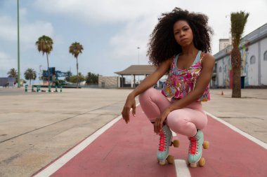 portrait of beautiful young afro woman on roller skates with urban background