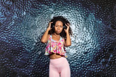 young black woman with headphones dancing to the rhythm of the music
