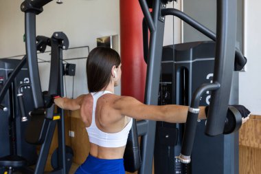 Bir kadın spor aleti kullanarak sırt egzersizi yapıyor, kaslarını güçlendiriyor ve fitness 'i geliştiriyor