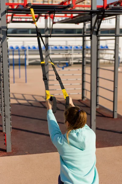 Outdoor fitness, openbaar sportveld. Een jonge sportvrouw doet een training op straat, — Stockfoto