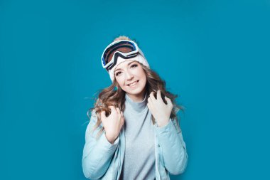 Şapkalı ve kar maskeli neşeli genç bir kadın. Kışlık ceketli bir kız.