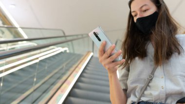 Yüzünde tıbbi maske olan genç bir kadın. Koronavirüs salgını sırasında solunum koruması..