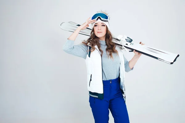 Chica sonriente esquiadora con sombrero y máscara para esquiar. Una joven en ropa para esquiar y actividades al aire libre. — Foto de Stock