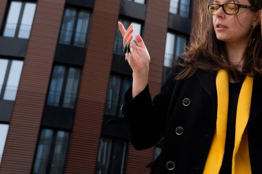 Apartman satın alma, başarılı bir emlak işlemi. Elinde anahtarlar olan mutlu bir kadın.,