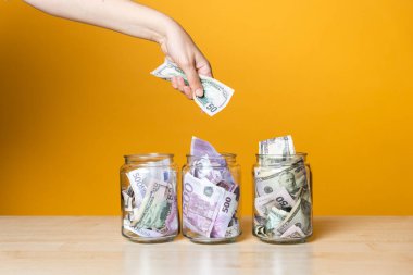 Çoklu para hesapları, konsept. Parlak sarı bir arka planda cam bir kavanozda dolar ve avro.