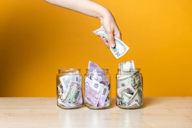Çoklu para hesapları, konsept. Parlak sarı bir arka planda cam bir kavanozda dolar ve avro..