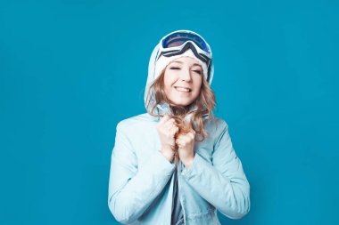 Şapkalı ve kar maskeli neşeli genç bir kadın. Kışlık elbiseli kız.