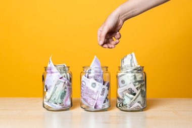 Çoklu para hesapları, konsept. Parlak sarı bir arka planda cam bir kavanozda dolar ve avro.