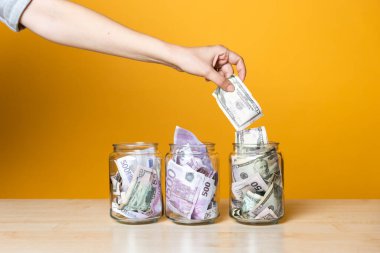 Çoklu para hesapları, konsept. Parlak sarı bir arka planda cam bir kavanozda dolar ve avro.