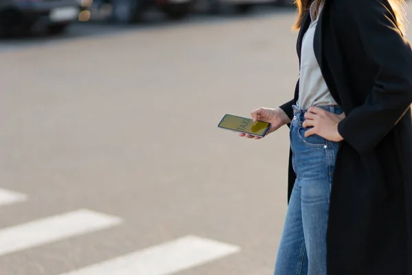 Mobiele taxidienst, moderne technologieën in de stad. Een vrouw gebruikt haar telefoon om een auto te zoeken.. — Stockfoto