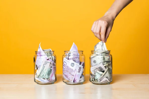 Çoklu para hesapları, konsept. Parlak sarı bir arka planda cam bir kavanozda dolar ve avro.