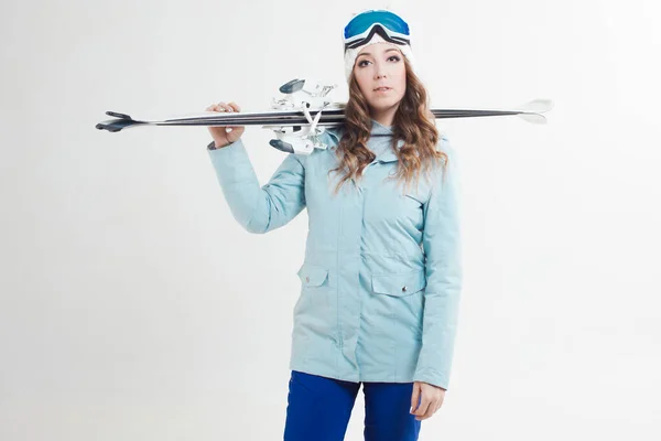 Усміхнена дівчина лижник на білому тлі, портрет в студії. Молода жінка в зимовому одязі та лижному спорядженні — стокове фото