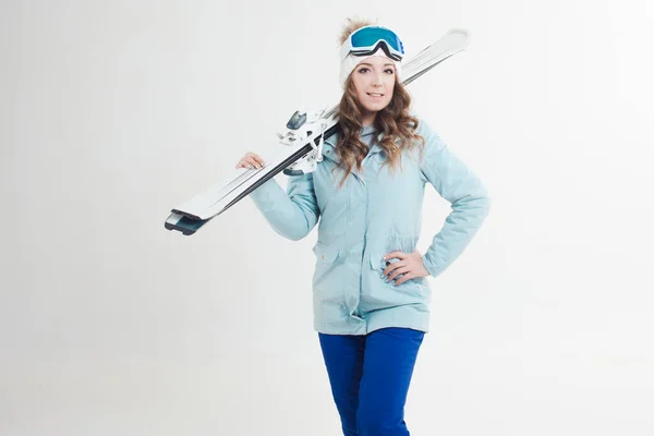 Усміхнена дівчина лижник на білому тлі, портрет в студії. Молода жінка в зимовому одязі та лижному спорядженні — стокове фото