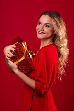 Bir hediye al, kırmızı elbiseli mutlu genç bir kadın yılbaşı, Noel ya da doğum günü için güzel bir sürpriz aldı..