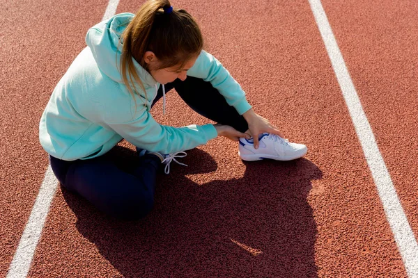 Sports injuries, a young female athlete kneading an ankle, sprained ligaments or muscles.