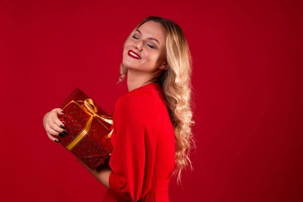 Get a gift, a happy young woman in a red dress got a nice surprise for new year, Christmas or birthday.