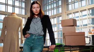 Küçük işletme, terzi dükkanı. Genç bir kadın sahibi ya da çalışanı sevkiyat için eşya topluyor