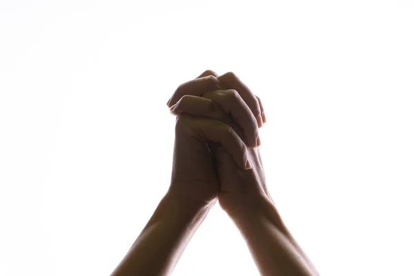 Bidden kruiste handen op een witte achtergrond. Licht van boven. Handen gevouwen in gebed. — Stockfoto