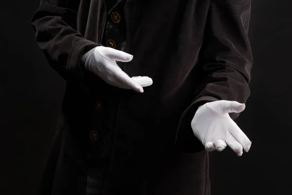 Hand gestures. Showman or magician illusionist in white gloves on a black background. — Stock Photo, Image