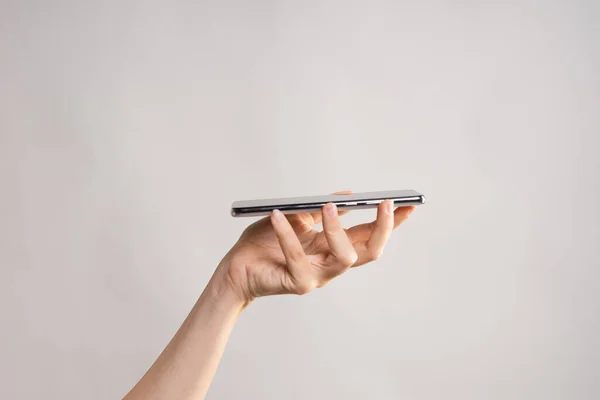 Slim modern smartphone, use the Internet or apps. A womans hand holds the phone horizontally.