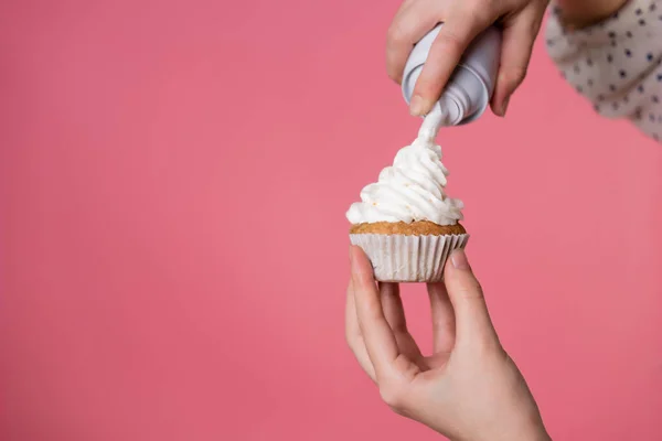 Young charming female pastry chef decorates a muffin with whipped cream. — Stock Photo, Image