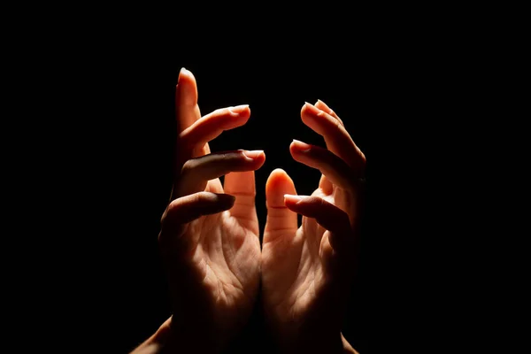 Beautiful folded hands with light on top, black background. Prayer or creating a miracle. — Stock Photo, Image