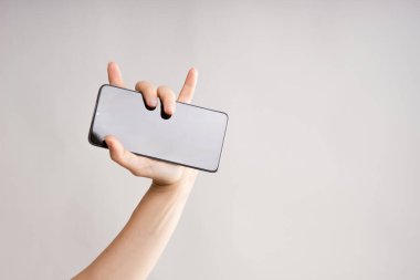 Bir kadının elinde dokunmatik ekranı olan havalı akıllı telefon, bir rockçı hareketi..