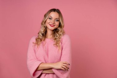 Sıcak pembe kazak giyen genç ve çekici bir kadın el hareketi yapar..