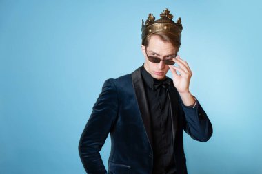 Gözlüklü, konseptli başarılı bir iş adamı. Kafasında taç olan, smokinli, genç, karizmatik bir adam..