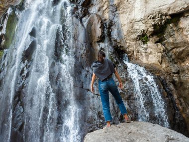 Ormanda turizm, dağ şelalesinin arka planında genç bir kadın.,
