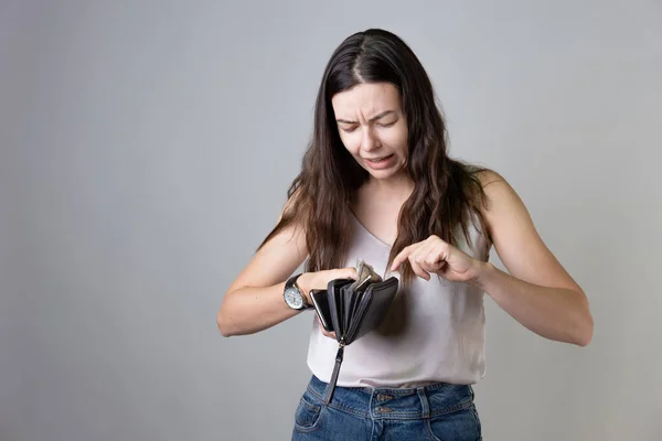 Harcamalar geliri aşıyor, üzgün genç kadın aile bütçesini yönetiyor.,